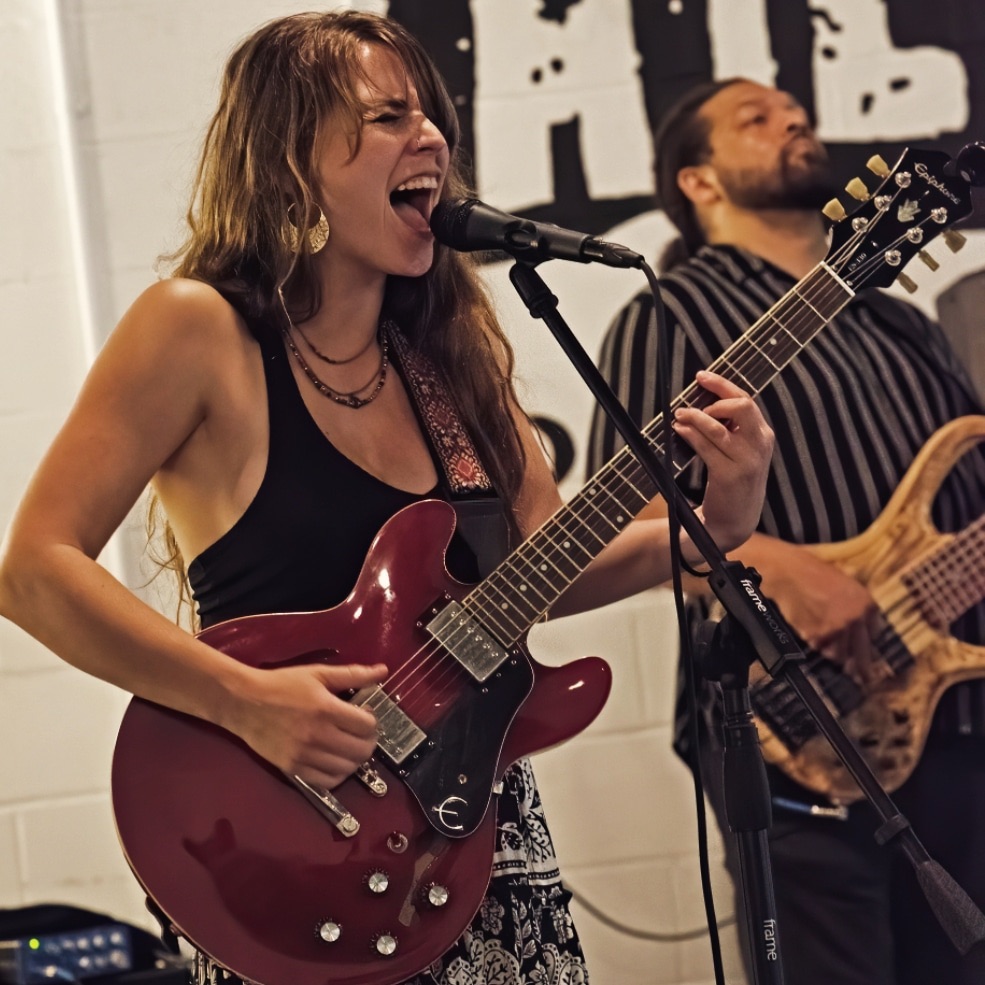 Cassidy belting at the mic with a cherry-red electric guitar