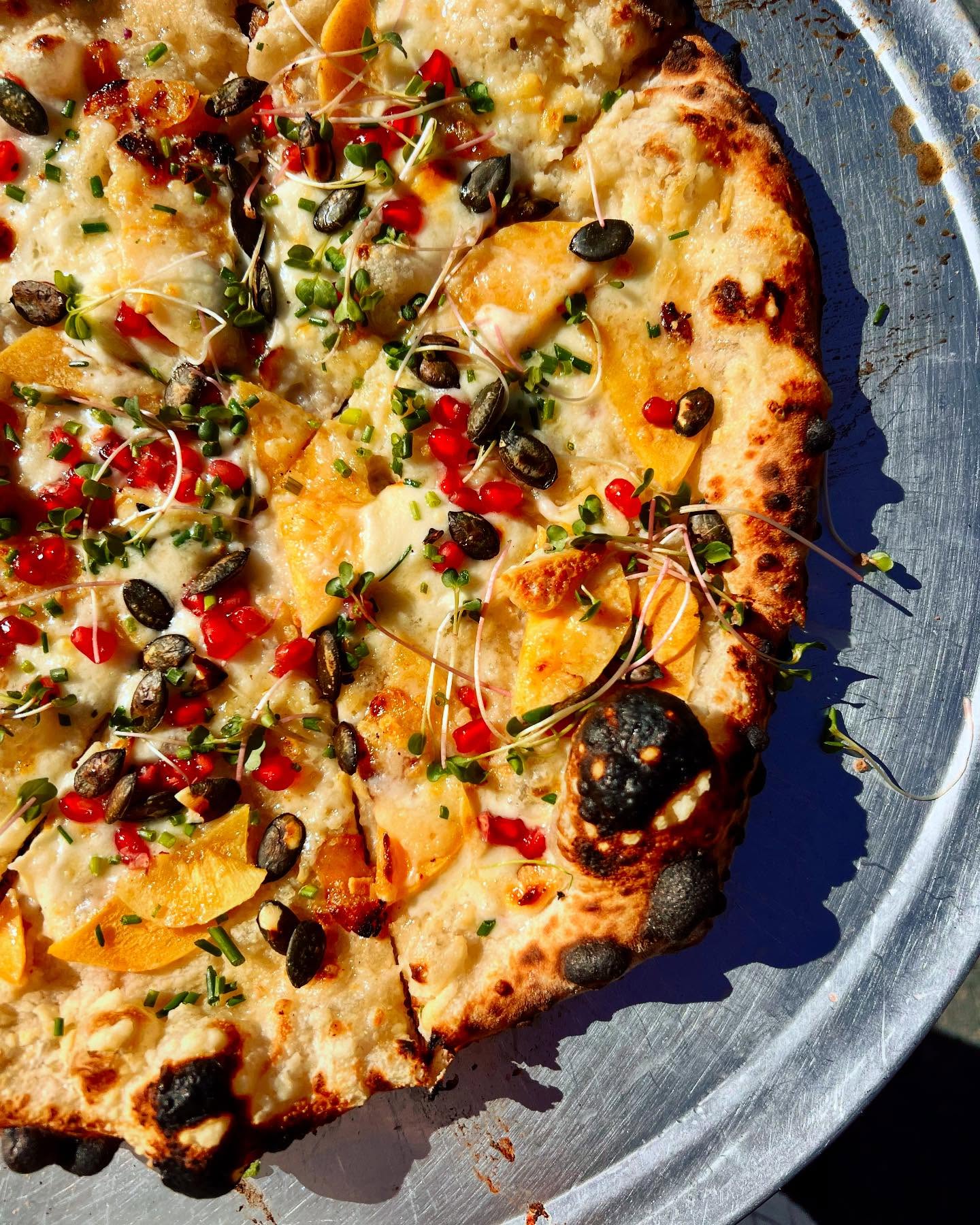 Seasonal white pie with peaches, squash, microgreens and chili