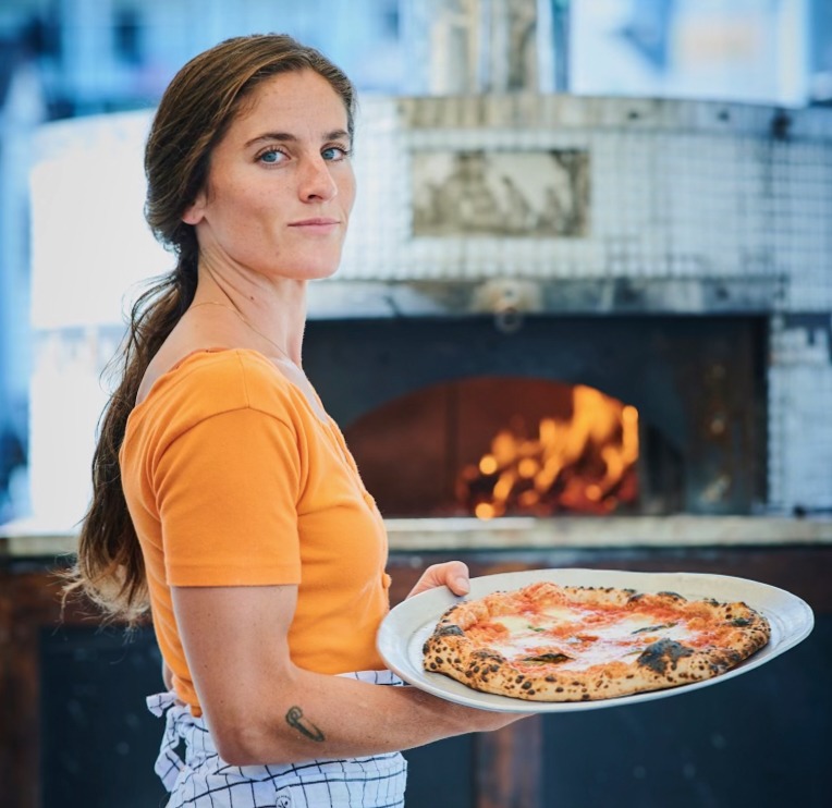 Pizzaiolo Emily Downs of Emily's Hearth, in front of the wood-fired oven